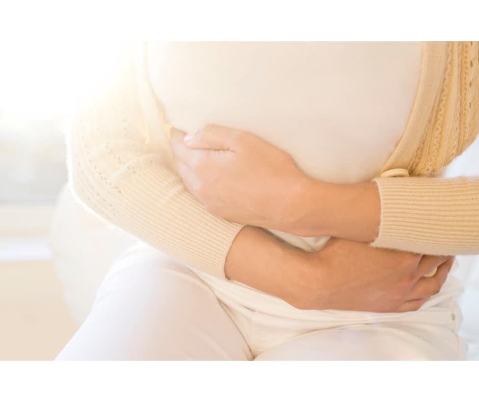 Woman holding stomach in discomfort, highlighting the use of painkillers for period pains and menstrual cramp relief